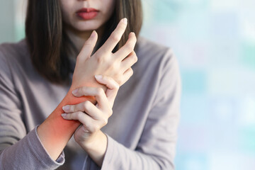 A woman squeezes a wrist that is inflamed due to arthritis.
