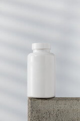  Mockup is a white jar with pills or vitamins on a podium. Medical preparations.
