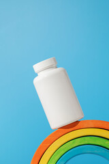 The layout is a white jar with vitamins for children on the podium in the form of a rainbow. vitamins for children