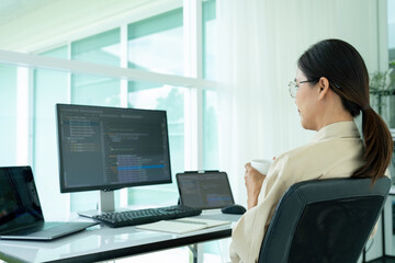 Female IT programmer relaxes at office desk.