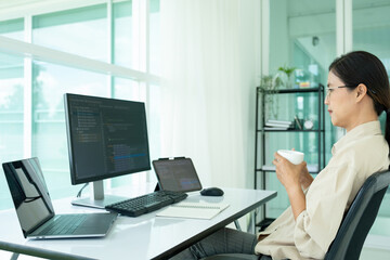 Naklejka na ściany i meble Female IT programmer relaxes at office desk.