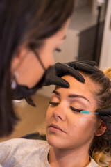 Fototapeta premium Applying mascara to eyelashes of a woman in a salon