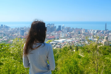 Woman tourist admiring cityscape of coastal Batumi city and sea from mountain in Georgia. Travel...
