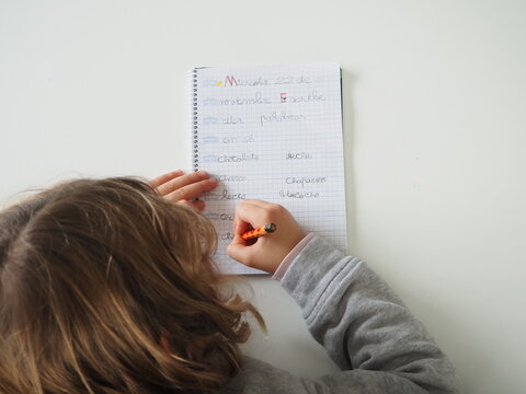 Ni&ntilde;a escribiendo palabras en mesa blanca vista superior