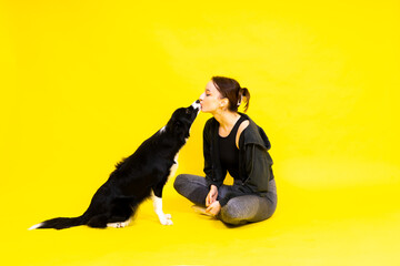 Cute young woman kisses and hugs her puppy border collie dog. Love between owner and dog.