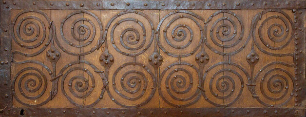Türdetail,  Alte Holztür mit einem metallischen, spiralförmigen Eisenbeschlag
