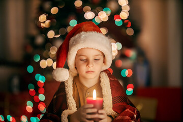 Portrait of a boy holding a christmas candle at home on christmas eve.