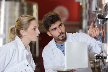 male and female colleagues with laptop working in brewery