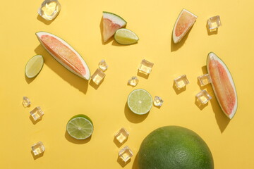 View from above of pomelo, lemon and ice randomly arranged on a yellow background. Fresh summer...