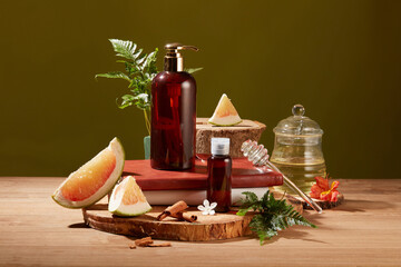 Front view of pomelo essential oil in a glass jar, accompanied by a brown cosmetic bottle, pomelo,...