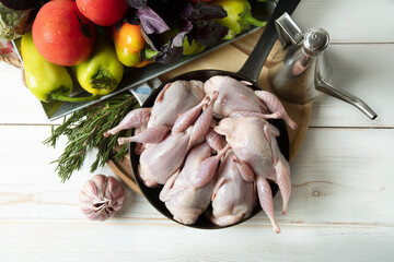 Raw quail with fresh vegetables on the table before cooking