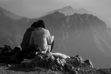 They look at the landscape.
A couple of friends admire the landscape. Subjects from behind. Black and white photo.