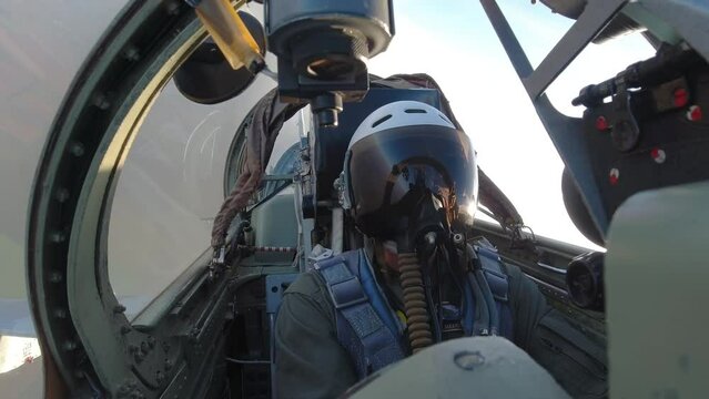 A pilot in a helmet inside the cockpit of a fighter