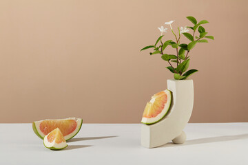Pomelo segments are placed on a white table with a vase of flowers. Free space for design and...