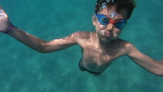 The dark-haired boy slowly dives into the blue sea