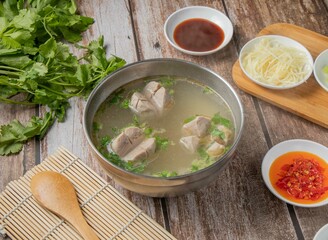 Gongwan soup or Gong wan pork balls meat soup with chilli sauce, noodles, spoon and chopsticks served in bowl isolated on napkin top view of hong kong food