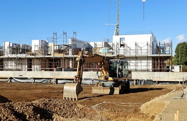 Excavator in front of modern building under construction.