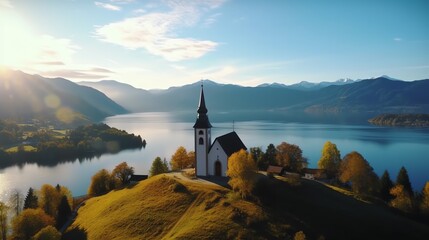 a church on a hill with a lake and mountains in the background - obrazy, fototapety, plakaty