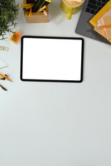 Flat lay, top view digital tablet with white empty screen, coffee cup and laptop on white table
