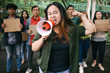 Woman with raised fist shouting through megaphone for gender equality, human rights or justice with...