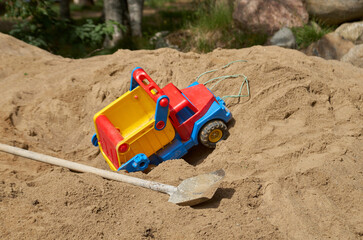 Childhood and adult life: a junk truck and a real shovel on a pile of sand
