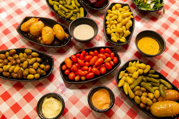 Olives with pits, cherry tomatoes, pickled peppers and cucumbers with various sauces are an appetizer before main course on the table. Lebanese cuisine