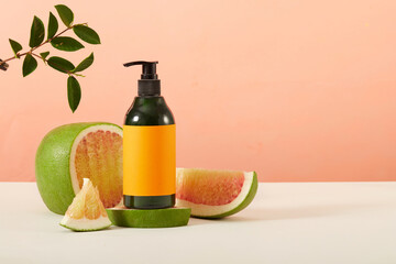 An unbranded cosmetics bottle is displayed on a podium with fresh pomelo. Mockup for product advertising. Pomelo essential oil helps stimulate hair growth quickly and helps strengthen hair.