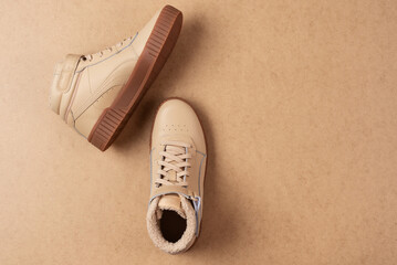 Pair of leather beige unisex sneakers on beige background - obrazy, fototapety, plakaty