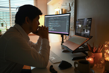 Side view of focused software developer programming on desktop computer