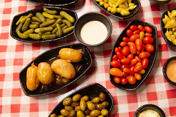 Olives with pits, cherry tomatoes, pickled peppers and cucumbers with various sauces are an appetizer before main course on the table. Lebanese cuisine