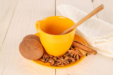 Chocolate cookies, cinnamon, star anise, coffee beans on a ceramic plate with a cup on a wooden table.