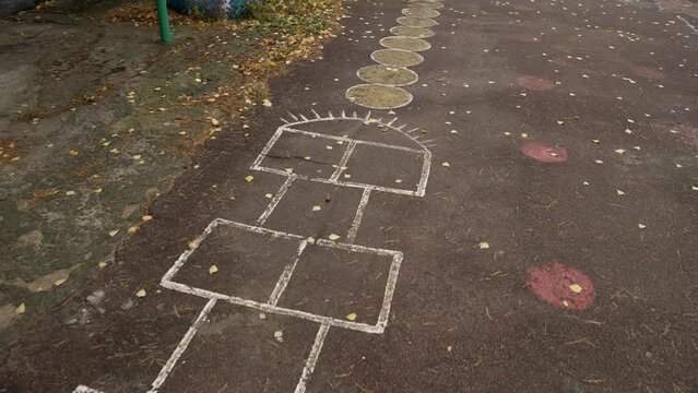 Empty garden of the elementary school  and playground Hop Scotch 
Playing classics and other children's drawings on the asphalt in the park. Painted with colorful paints
asphalt with fallen leaves 