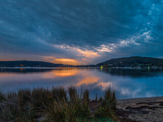 Heavy cloud covered sunrise over the bay with colour and reflections
