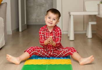 Sport and health concept. A little boy 4 years old in red checkered pajamas is working out on a...