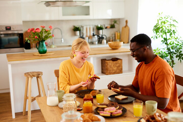 Multiracial couple enjoying breakfast together at home