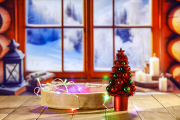 Wooden retro yellow table and blurred background of window sill. Christmas tree and empty space for your decoration. Natural light and magic time. Mockup background and cold december time.