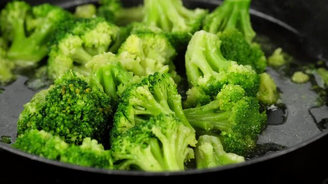 Chef stirring and frying broccoli on a pan. Healthy food, vegetarian cuisine