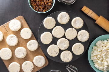 Cheesecakes made from cottage cheese and raisins. Prepare food for breakfast. Syrnik pancake. Round cheese cake on black background