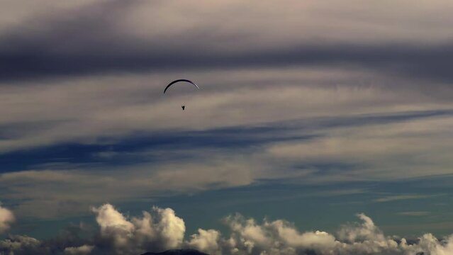 Aerial View on a Paraglider Flying with a Beautiful Cloudscape and Mountain in a Sunny Day in Ticino, Switzerland.