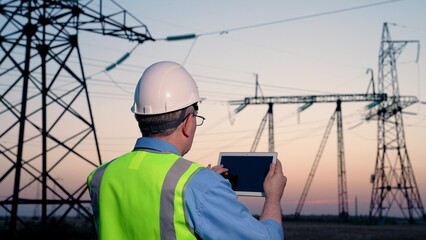 Electrician worker uses tablet on electric project site. Man electrician streamlines coordination...