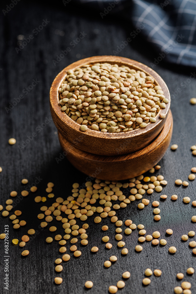 Canvas Prints Uncooked lentil legumes in bowl on black table.