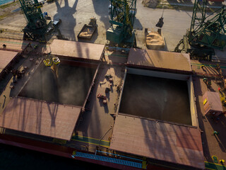 Aerial view of big cargo ship bulk carrier is loaded with grain of wheat in port at sunset