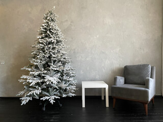 Snow-covered christmas tree in grey room interior for new year