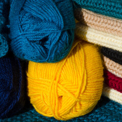 Balls of wool yarn, knitted patterns and hooks.