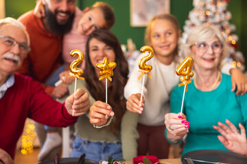 Family holding numbers 2024 while having Christmas dinner at home
