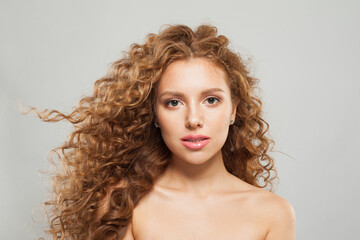 Naklejka premium Nice young fashion model woman with natural makeup, clear skin and curly hairstyleposing on white background