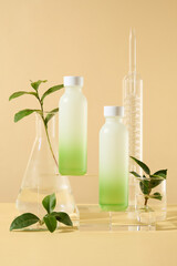 Set of cosmetic bottles on glass podiums with green tea leaves and lab glassware on beige background. Product and promotion concept for advertising cosmetic of green tea extract. Front view