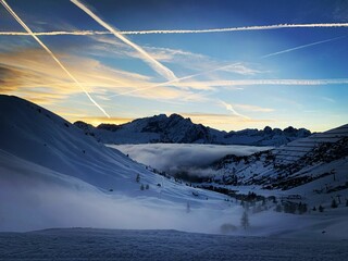 Snow-covered mountain peaks, with several airplanes in the sky leaving trails of vapor