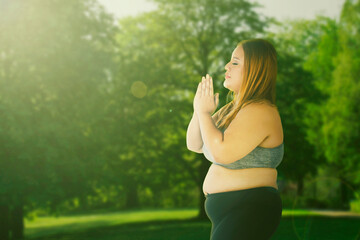 Naklejka na ściany i meble Overweight caucasian beautiful overweight woman doing meditation exercises at park