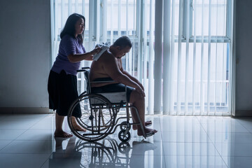 Wife or nurse wiping Sick Overweight man sitting on a wheelchair